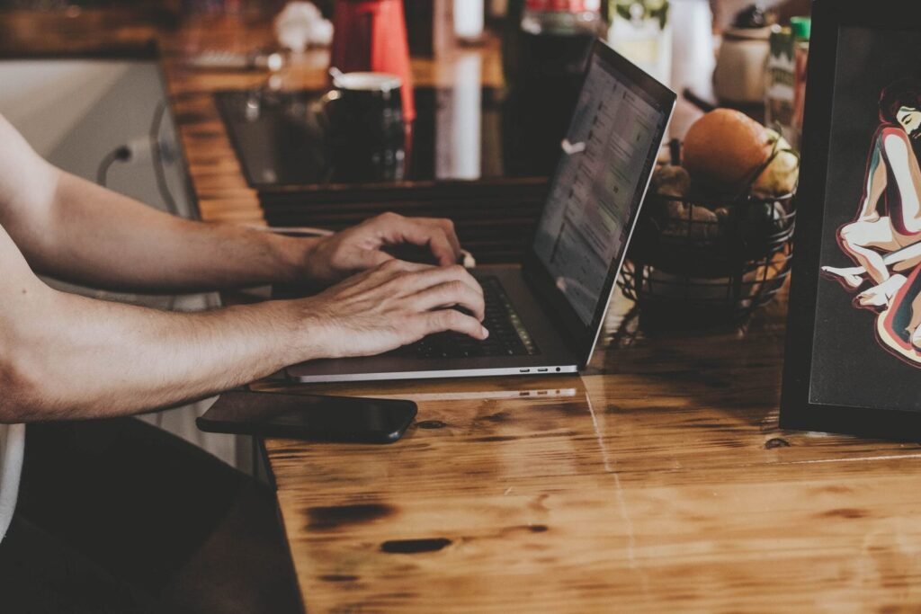Mãos digitando em um notebook sobre bancada de madeira